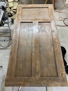 a wooden table sitting on top of a floor next to a pile of wood planks