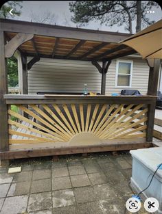 a wooden bench sitting on top of a patio next to a building with an umbrella over it