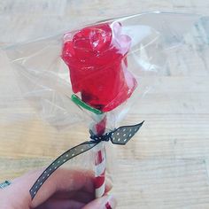 a person holding a candy cane with a red rose in it's wrapper