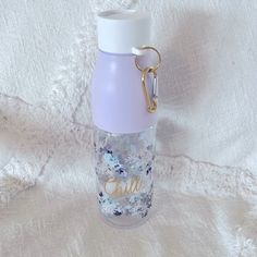 a purple and white water bottle sitting on top of a bed