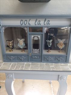 an old fashioned china cabinet is painted blue and has ornate carvings on the glass doors