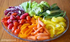 a glass bowl filled with vegetables on top of a wooden table