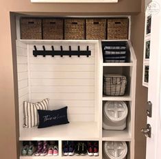 an organized mud room with white shelves and baskets