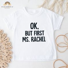 "\"Ok, but first Ms. Rachel\" short sleeve shirt for your little one!  Vinyl Colors Include: Please enter the vinyl color in the personalization box below.)  - Classic White  - Glitter White  - Classic Black - Glitter Black   - Glitter Pink  This shirt is made with a soft cotton fabric that is gentle and comfortable against your baby's delicate skin | 100% cotton. **WASHING / CARE INSTRUCTIONS** - Hand wash or machine wash inside-out in cold or warm water. - Mild detergent. - Low heat dryer or l Basic Short Sleeve Shirt With Funny Text, Cotton Short Sleeve Shirt With Name Print, Family Matching Fitted Shirt With Short Sleeves, Cute Short Sleeve Shirt With Name Print, Cotton Short Sleeve Shirt With Funny Text, Dancing Fruit, Hey Bear, Ms Rachel, Simple Songs