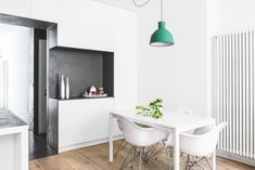 a white table with four chairs and a green light hanging from it's ceiling