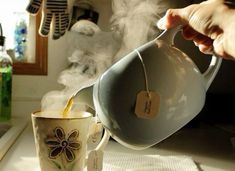 a person pouring tea into a cup with steam rising from it