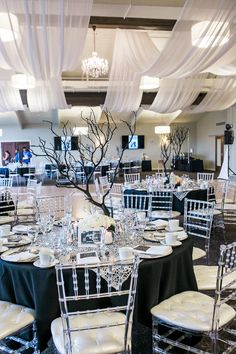 tables and chairs are set up for a formal function with white drapes on the ceiling