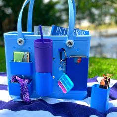 a blue tote bag sitting on top of a purple and white blanket next to other items