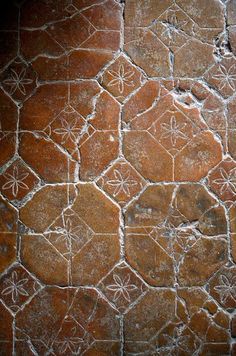 an old stone wall with white flowers and leaves on it's surface, as well as some other designs