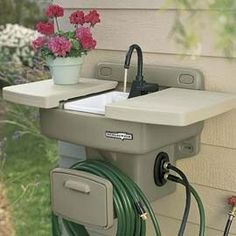 a sink with a hose connected to it and a potted plant in the corner