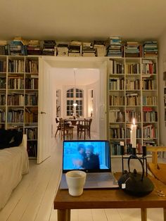 a laptop computer sitting on top of a wooden table in front of a bookshelf