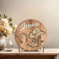 a wooden plaque with a cowboy hat and boots on it sitting next to vases