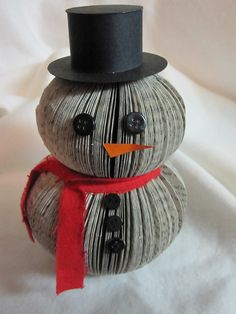 a snowman made out of books with a black top hat and red scarf around his neck