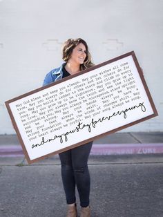 a woman holding up a framed sign with writing on it