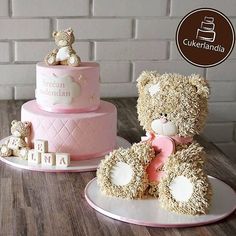 two teddy bears sitting next to a pink cake