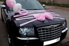 a black car decorated with pink and white balloons