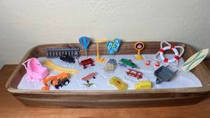 a sandbox filled with toys sitting on top of a wooden table next to a white wall