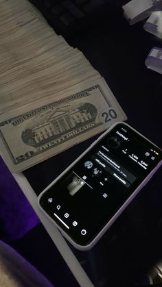 a cell phone sitting on top of a table next to a money bill and keyboard