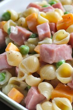 pasta salad with ham and peas in a white bowl