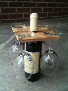 two wine glasses and a bottle sitting on a table with a wooden tray attached to it