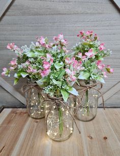 three mason jars with pink and white flowers in them