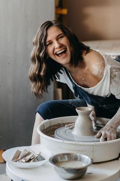 a woman smiles as she works on a pottery wheel