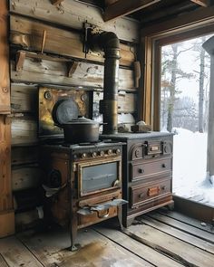 an old fashioned stove and oven in a room with wooden floors, walls and windows