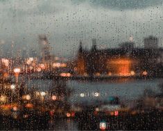 rain is falling down on the window and city lights are visible in the back ground