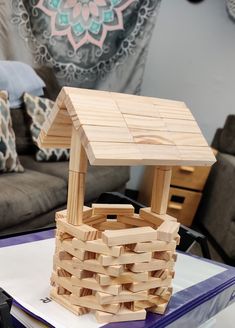 a small house made out of wooden blocks on top of a blue table in front of a couch