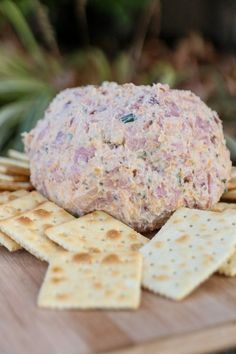 a cheese ball on top of crackers sitting on a cutting board