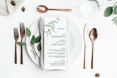 a place setting with silverware and greenery