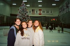 four girls standing in front of a christmas tree on an ice rink at the university of washington