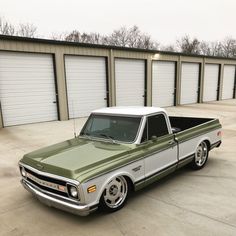 a green and white truck parked in front of garage doors