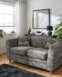 a living room scene with focus on the couch and rugs in front of the window