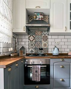 a stove top oven sitting inside of a kitchen next to a wooden countertop and white cabinets