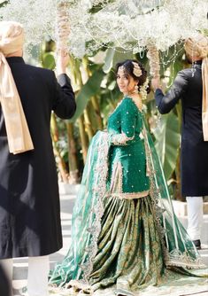 a woman in a green lehenga walking down the street