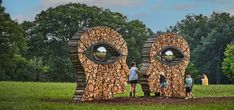 people standing in front of two large sculptures made out of logs