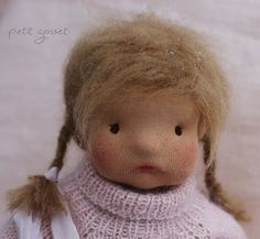 a doll with blonde hair wearing a pink sweater