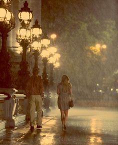 two people walking down the street in the rain