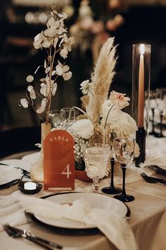 the table is set with flowers, candles and place settings for an elegant wedding reception