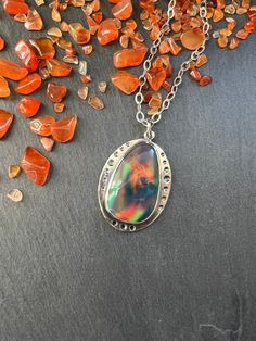 "This stone is a man made aurora borealis opal.  It has very interesting multicolored color play that reminds me of a galaxy inside.   The pendant is made with sterling silver and the stone is set in a bezel setting. NOTE:  As with all opal, this is a soft stone so care will need to be taken to not scratch or damage it.  Always remove your jewelry prior to washing and showering.  Jewelry should always be the last thing you put on after applying makeup, perfume, hairspray, etc.  Never wear soft stone jewelry while working out, or to bed, as this my cause unnecessary wear and tear and my damage the stone. Total length of the pendant is 38mm (approximately 1.5\"). Width is 28mm (approximately 1.13\"). When purchasing you have the option to purchase the pendant only or with your choice of chai Iolite Necklace, Applying Makeup, Bone Necklace, Color Play, Rhodolite Garnet, How To Apply Makeup, Opal Necklace, Aurora Borealis, Sterling Silver Necklace