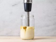 a bottle filled with liquid sitting on top of a wooden table next to a blender