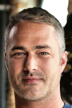 a close up of a person wearing a blue shirt and looking at the camera with a serious look on his face