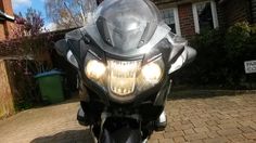 a motorcycle is parked in front of a house with its headlights on and the lights turned on