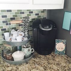 there is a coffee maker and cups on the counter