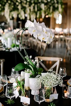 the table is set with white flowers and place settings