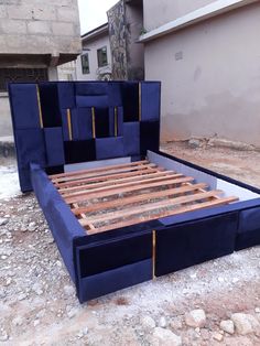 a blue bed frame sitting on top of a pile of dirt next to a building