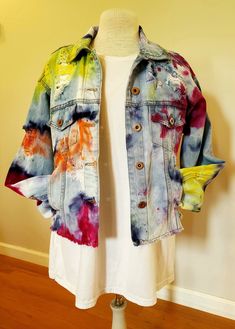 a woman's jean jacket with colorful paint splattered on it