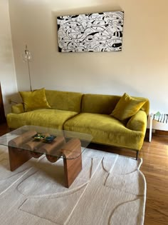 a living room filled with furniture and a large painting on the wall above it's glass coffee table