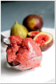 a white plate topped with ice cream next to two figs and a knife on top of it